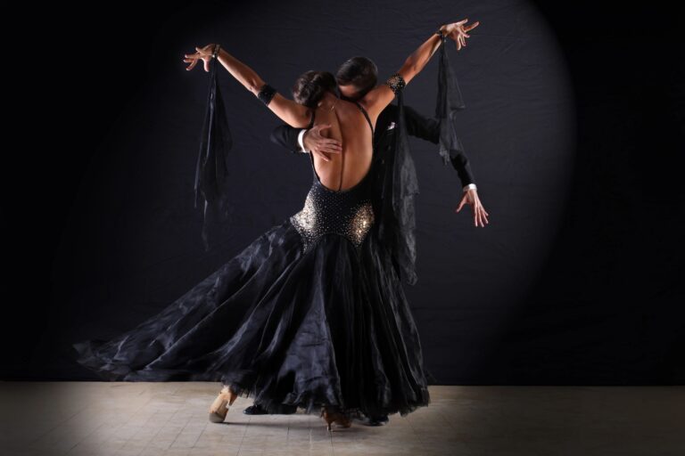 Professional ballroom dancer in an elegant black gown performing with her partner.